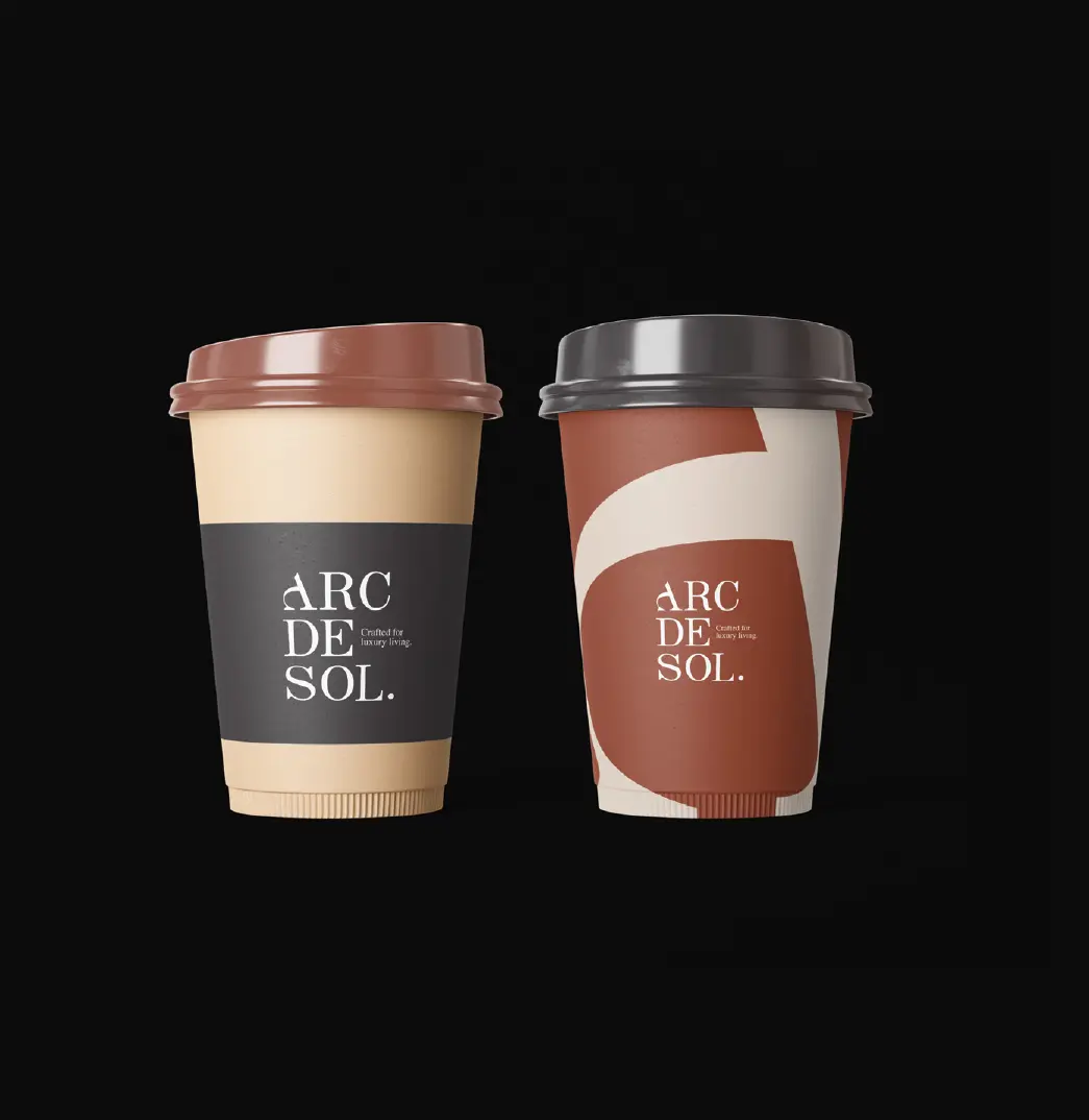 Two Arc de Sol coffee cups, one stone with a black band and one with a warm red arc