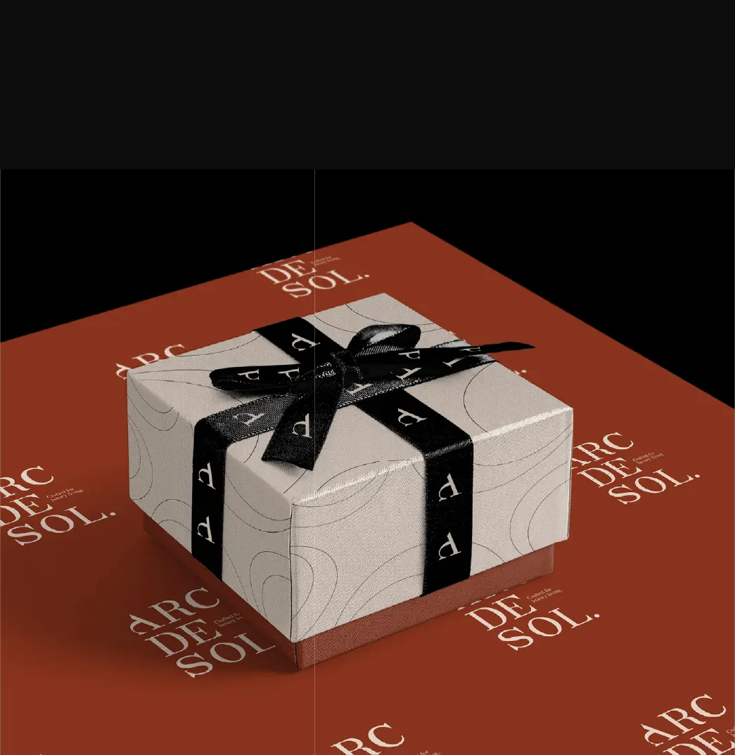 Arc de Sol gift box in stone paper with arc lines, tied with black ribbon printed with the letter mark