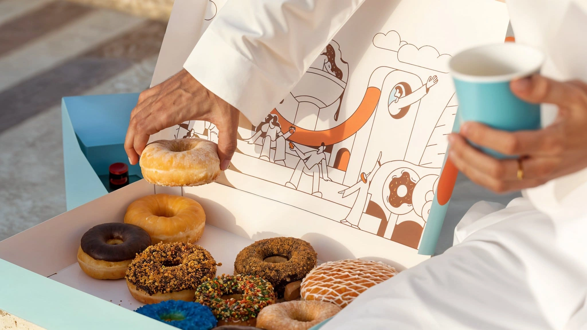 Donut Time Arabic logo دونت سعودي in chocolate brown on sky blue, with the orange smile forming the letter ت